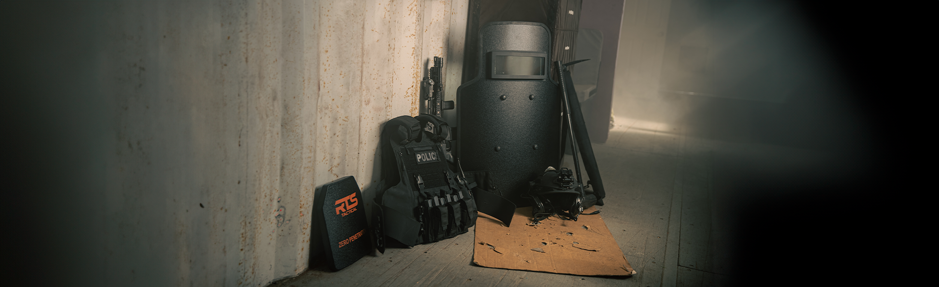 Three black tactical shields stand against a metal wall in a dimly lit room.