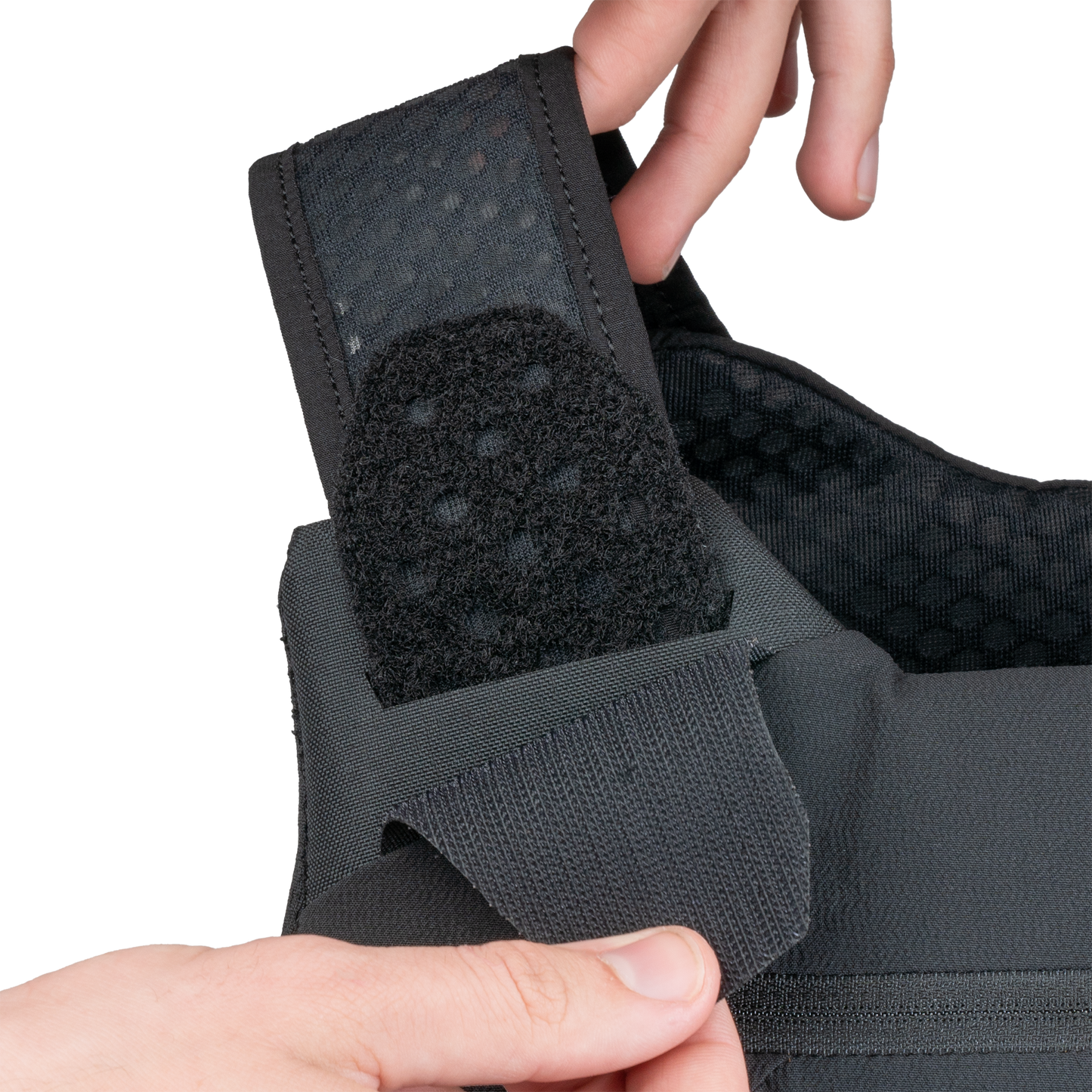 Close-up of hands adjusting the shoulder strap of a black tactical vest.