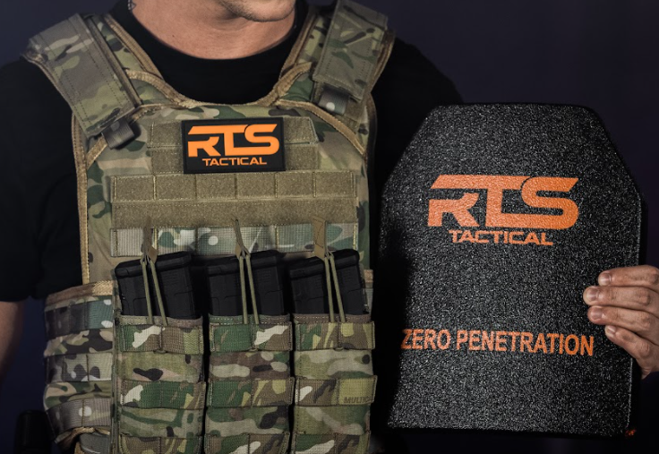 A person wearing a multicam tactical vest displays an RTS Tactical ballistic plate with "Zero Penetration" marking.