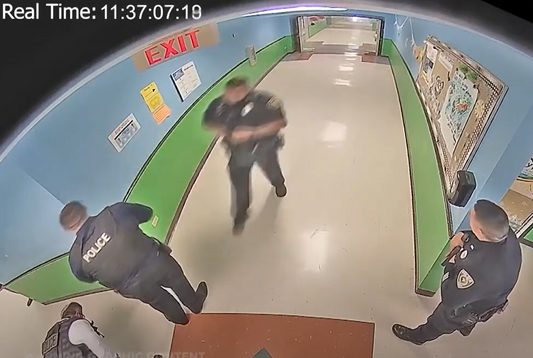 Four armed police officers in the Uvalde school hallways during an active shooter situation.