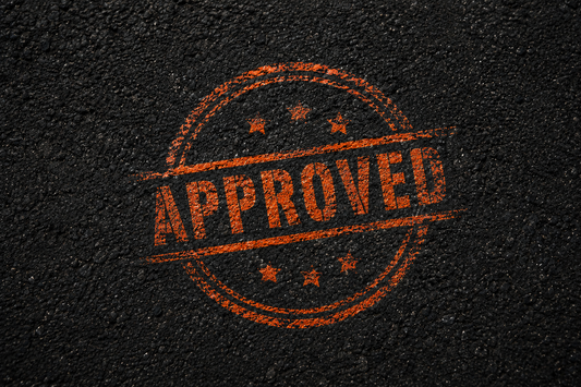 An orange "approved" stamp on asphalt 