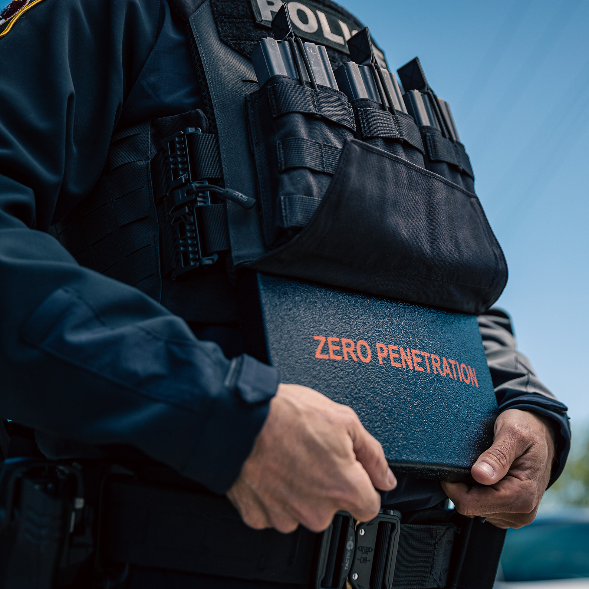 A police officer adjusts their tactical gear. The vest, labeled "POLICE," holds various tactical equipment.