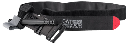 Black CAT tourniquet with a windlass, buckle, and red tip. The strap is labeled with medical specifications. Used for emergency bleeding control.
