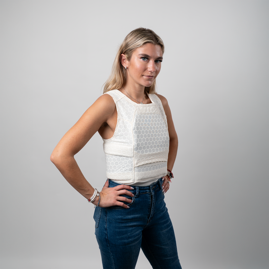 A woman standing confidently with hands on hips, wearing sleeveless compression shirt tactical armor
