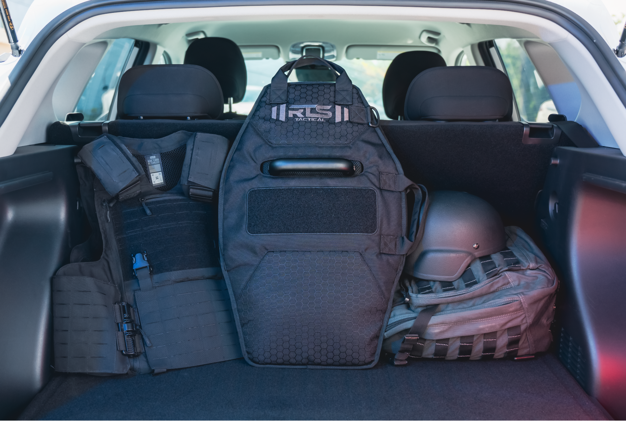 Vehicle trunk interior displaying RTS Tactical backpacks and tactical gear storage solutions arranged on seats and cargo floor.