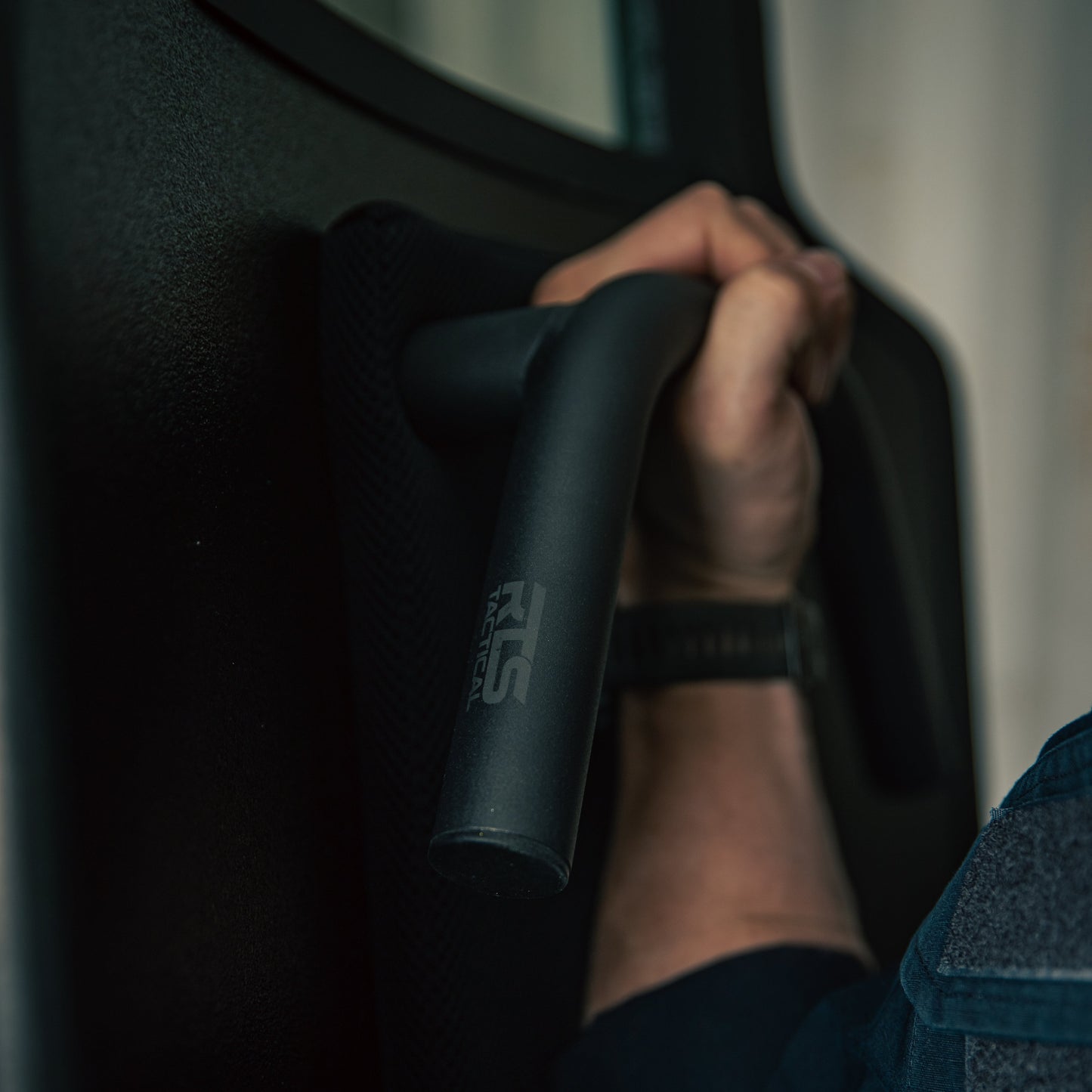 A person gripping a handle on the back of a black ballistic shield