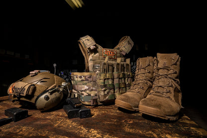 Tactical boots, a ballistic helmet and a plate carrier with ceramic plates placed on the ground.