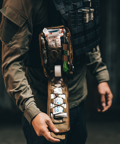 A man with the rapid deploy IFAK in Coyote Brown opened and secured on his plate carrier.