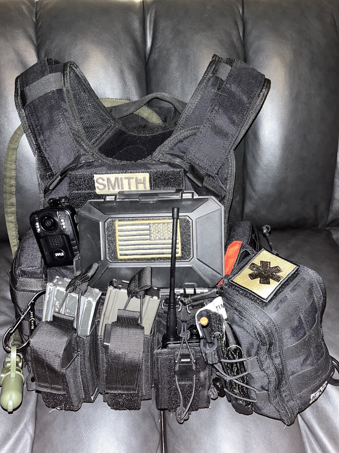 A black IFAK kit secured to the front of a black law enforcement plate carrier.