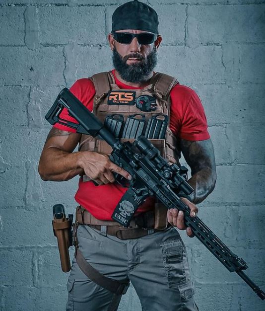 A man holding an AR wearing the RTS Tactical Premium Level IV Ceramic body armor kit.